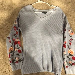 A knit blue sweater with embroidered flowers